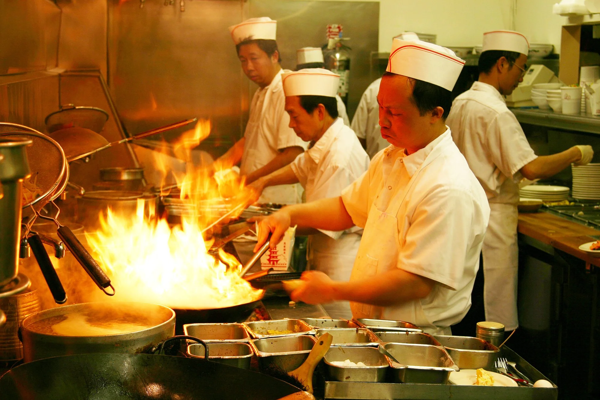 Chefs cooking over open wok flames in the Chinese Canteen kitchen